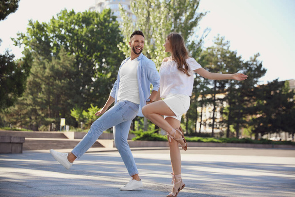 Lovely young couple dancing together outdoors on sunny day - Foto, afbeelding
