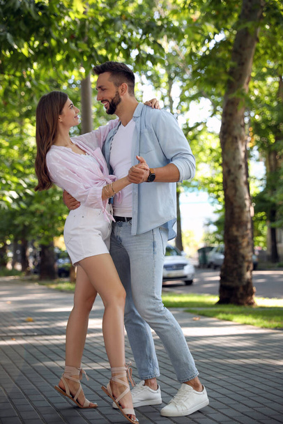Lovely young couple dancing together outdoors on sunny day - 写真・画像