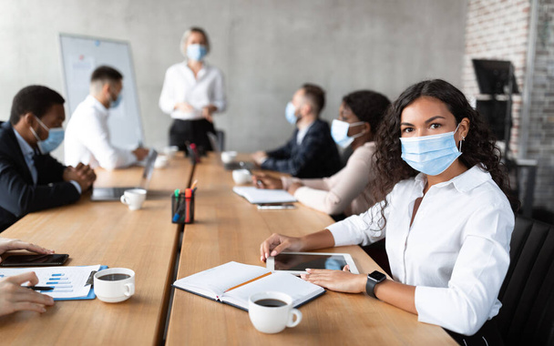 Бізнес-леді в масці для обличчя сидячи на корпоративній зустрічі в офісі
 - Фото, зображення