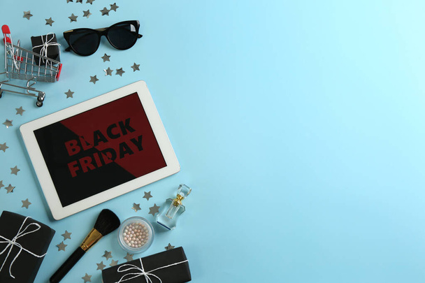 Flat lay composition with tablet, gifts and accessories on light blue background, space for text. Black Friday sale - Foto, Bild