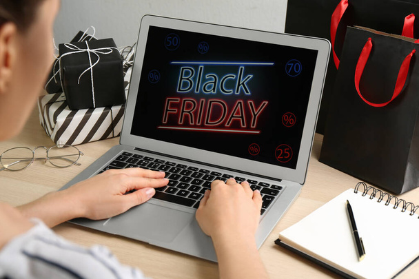 Woman using laptop with Black Friday announcement at wooden table, closeup - Foto, immagini