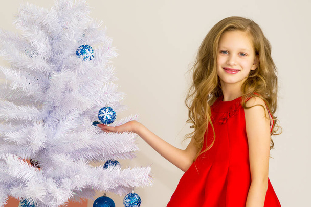 Girl Posing Next to White Christmas Tree Holding Blue Bauble. - Фото, изображение