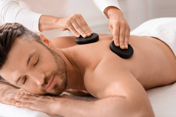 Closeup of man having hot stone massage at luxury spa - Photo, Image
