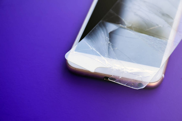 Una protezione dello schermo del telefono cellulare in vetro rotto viene posizionata sullo schermo del telefono cellulare. - Foto, immagini