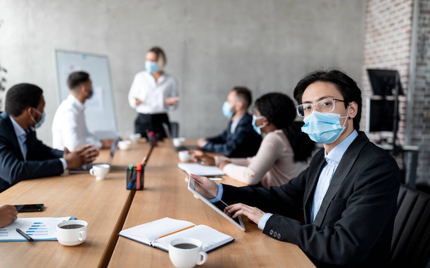 Asian Businessman Entrepreneur In Face Mask Sitting In Modern Office - Valokuva, kuva