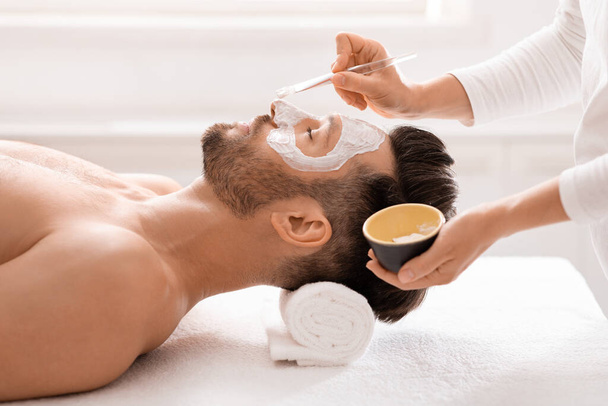 Bearded man getting face treatment at spa salon - Photo, Image