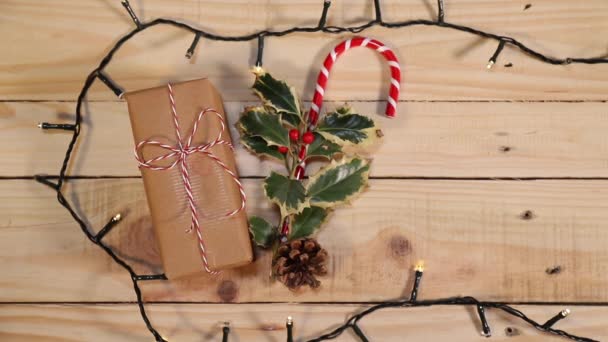 Noel Baba 'nın mükemmel yardımcısı için Noel aksesuarları: kutsal yapraklar, bir şeker kamışı, paketlenmiş bir hediye ve neşeli ve neşeli bir Noel için yumuşak ışıklar.. - Video, Çekim