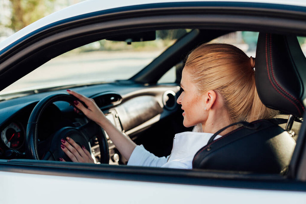 Piękna blond kierowca za kierownicą samochodu na drodze - Zdjęcie, obraz