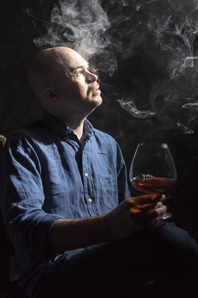 Solid bald man in shirt with glass of whisky and fume studio portrait. - Photo, image