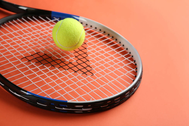 Tennis racket and ball on orange background, closeup. Sports equipment - Фото, зображення