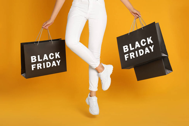 Woman with shopping bags on yellow background, closeup. Black Friday - Photo, Image