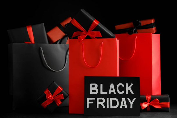 Paper shopping bags and gift boxes on dark background. Black Friday sale - Foto, imagen