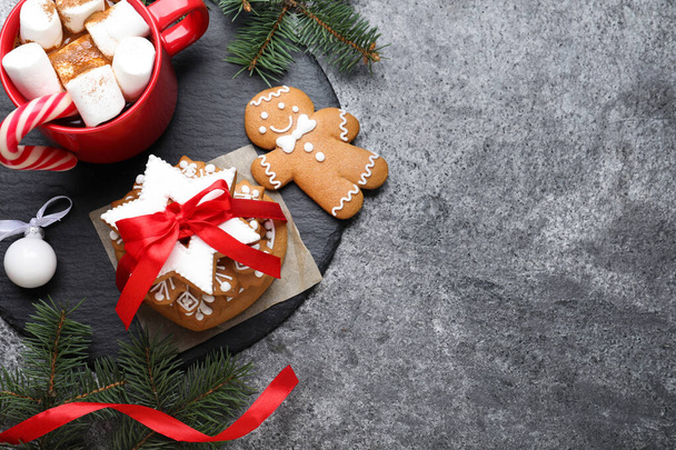 Decorated Christmas cookies and cup of delicious drink on grey table, flat lay. Space for text - Photo, Image