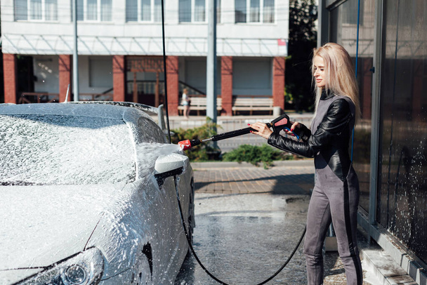 Piękna blondynka myje samochód w myjni samochodowej - Zdjęcie, obraz