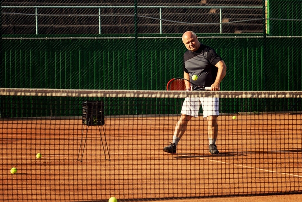An aged man plays tennis on the court. Active lifestyle and health. - Fotoğraf, Görsel