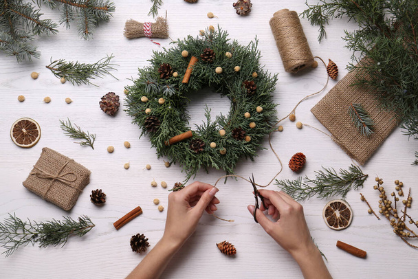 Florist making beautiful Christmas wreath at white wooden table, top view - Fotoğraf, Görsel