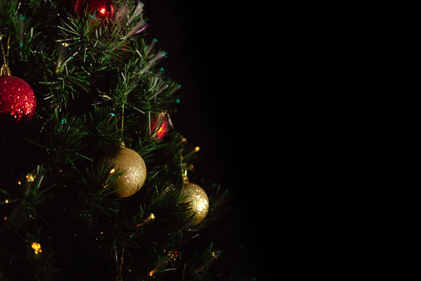 Grote mooie glanzende gouden kerstbal close-up op de achtergrond van een stralende kerstboom. Dure interieur decoratie. Cadeauwinkel. - Foto, afbeelding