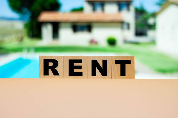 Yazlık evin arka planındaki küplere "RENT" kelimesi. Ortalama bir aile için daire kiralamanın maliyeti. - Fotoğraf, Görsel