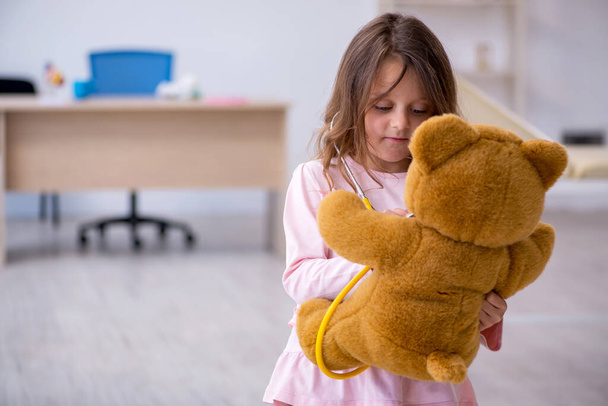 Μικρό κορίτσι κρατώντας αρκουδάκι παιχνίδι περιμένει το γιατρό στην κλινική - Φωτογραφία, εικόνα
