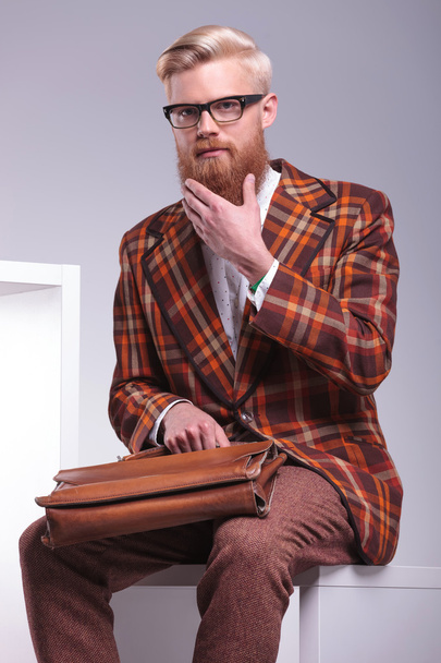 Hombre de moda sentado y jugando con su barba larga
 - Foto, Imagen