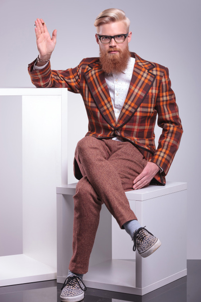 Модный бородатый мужчина курит сигарету и машет рукой
 - Фото, изображение