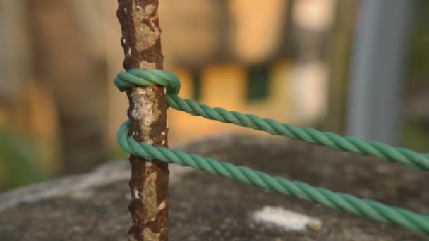 Una cuerda está atada en un nudo alrededor de un poste de la cerca, cuerda atada Hitch Nudos en un poste de hierro oxidado aislado del fondo. - Metraje, vídeo