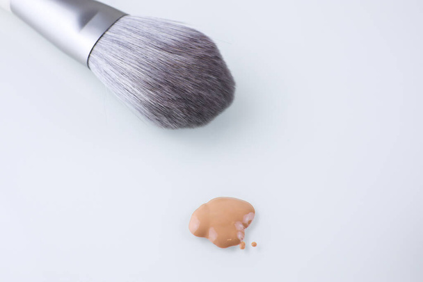 a makeup brush and a drop of Foundation for the face on an isolated background - Fotografie, Obrázek
