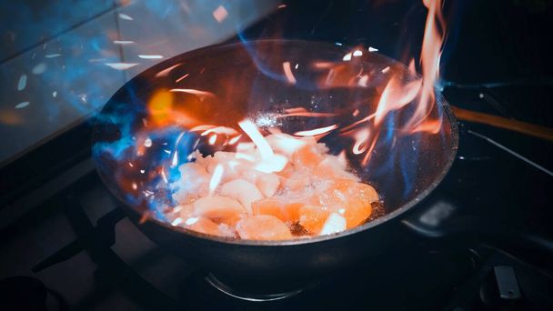 Open fire in a skillet the apple and orange are fried. home kitchen - 写真・画像