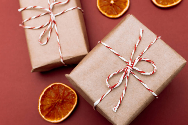 Christmas style rustic brown paper package tied up with strings on red background - 写真・画像