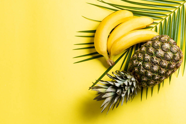 Pineapple,banana and tropical palm leave on yellow background. Top view - Фото, изображение