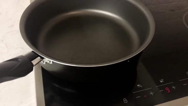 De kokkin bevat een elektrisch fornuis en giet olie in de koekenpan. - Video