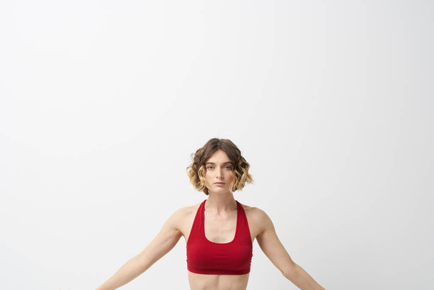 a lány jógázik egy könnyű háttérrel Vörös póló gesztikulál a kezével - Fotó, kép