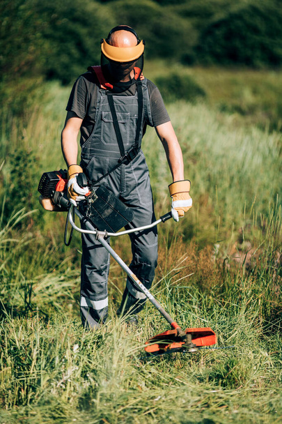 jardinero macho corta la hierba con una cortadora de césped. - Foto, Imagen