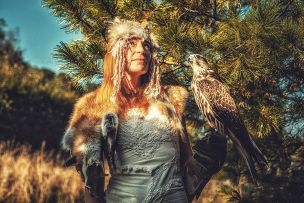 beautiful shamanic woman with eagle in the nature. - Photo, Image