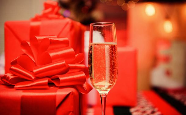 Glass of champagne close up. New year traditional attribute. Happy new year and merry christmas. Champagne elegant glass. Glass filled sparkling wine or champagne near gift boxes. Celebrate new year - Fotó, kép