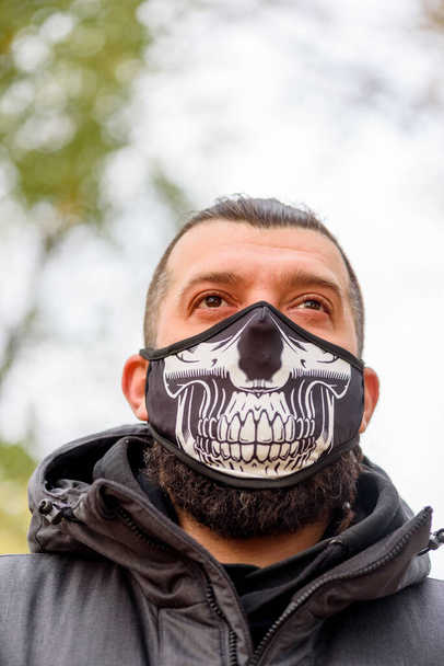 Sokakta yüzü maskeli, kışlık elbiseli bir adam var. Grip virüsü ya da koronavirüs enfeksiyonuna karşı korunmak için solunum cihazına bağlı bir erkek. Sokakta koruyucu maskeli bir adam. - Fotoğraf, Görsel