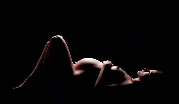 Pregnant woman on a black background - Photo, Image