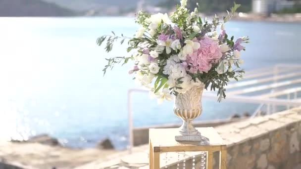 kecses váza egy csokor bazsarózsával, liziantusszal, delfiniummal és olajággal, esküvői helyszín dekoráció - Felvétel, videó