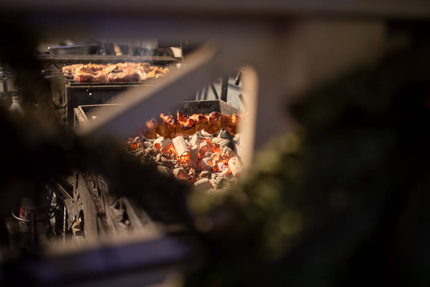 vlees op spiesjes wordt gebakken in een houtskoolgrill. zicht door het hek rooster. groot plan - Foto, afbeelding