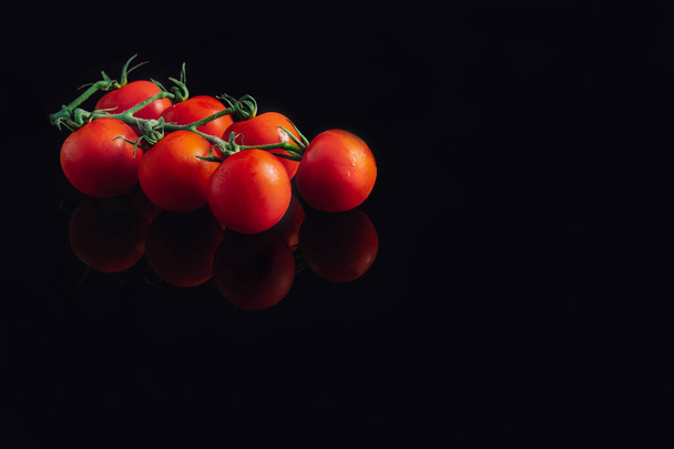 Cluster of cherry tomatoes on a black background Fresh and organic tomatoes. Reflection - Foto, afbeelding