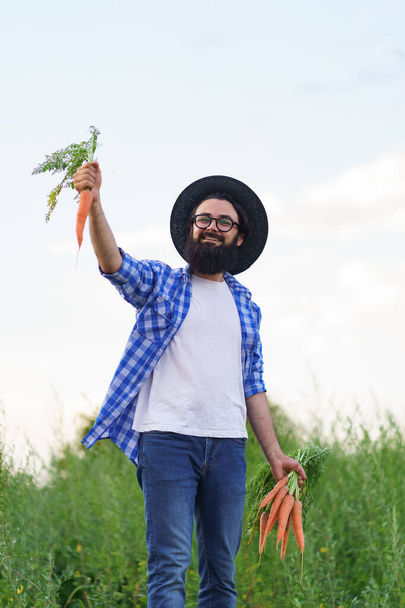 Happy man holding a bunch of carrots in his hands - Foto, imagen