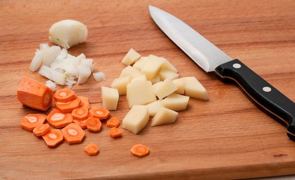 Cebolla, zanahorias y patatas en una tabla de cortar de madera
 - Foto, Imagen