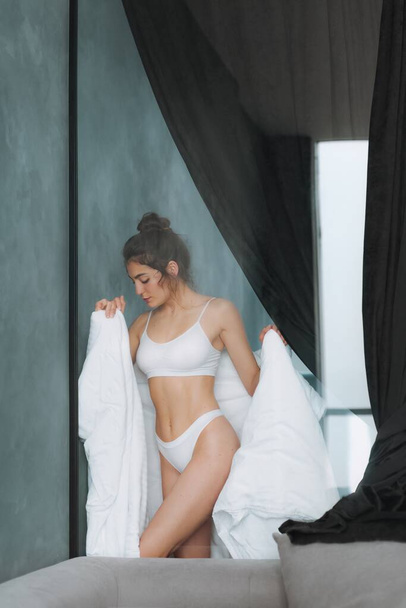 Flirtuje sexy dívka s bílou přikrývkou ve své ložnici. Dobré ráno - Fotografie, Obrázek