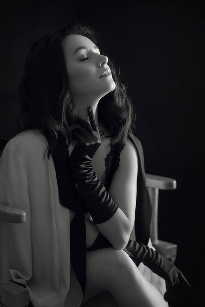 mooie jonge vrouw in zwart handschoenen op de stoel - Foto, afbeelding