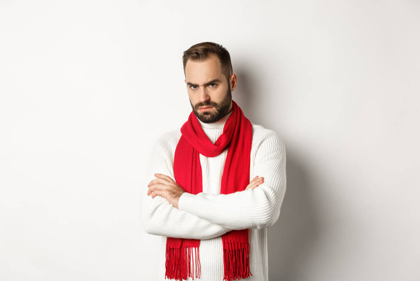 Bearded man looking angry and offended at you, cross arms on chest in defensive pose, sulking while standing in christmas sweater over white background - Foto, immagini