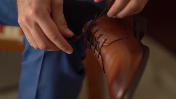 man zet op schoenen en stropdassen zijn schoenveters close-up - Video