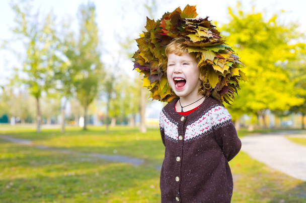 秋からの花輪で面白い少女の葉します。 - 写真・画像