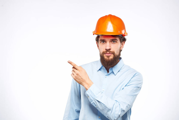 Man in orange hard hat industry engineer work professional light background - Foto, Bild