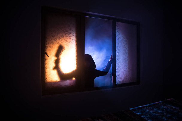 Silhouette einer unbekannten Schattenfigur auf einer Tür durch eine geschlossene Glastür. Die Silhouette eines Menschen vor einem Fenster in der Nacht. Gruselige Szene halloween Konzept der verschwommenen Silhouette von Wahnsinnigen. - Foto, Bild