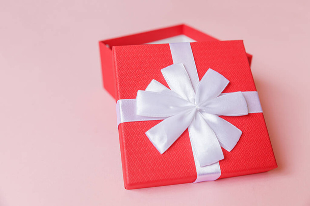 Vánoční novoroční narozeninová valentýnská oslava představuje romantický koncept. Jednoduše minimální design červené dárkové krabice izolované na pastelově růžové barevné pozadí. Flat lay top view copy space - Fotografie, Obrázek